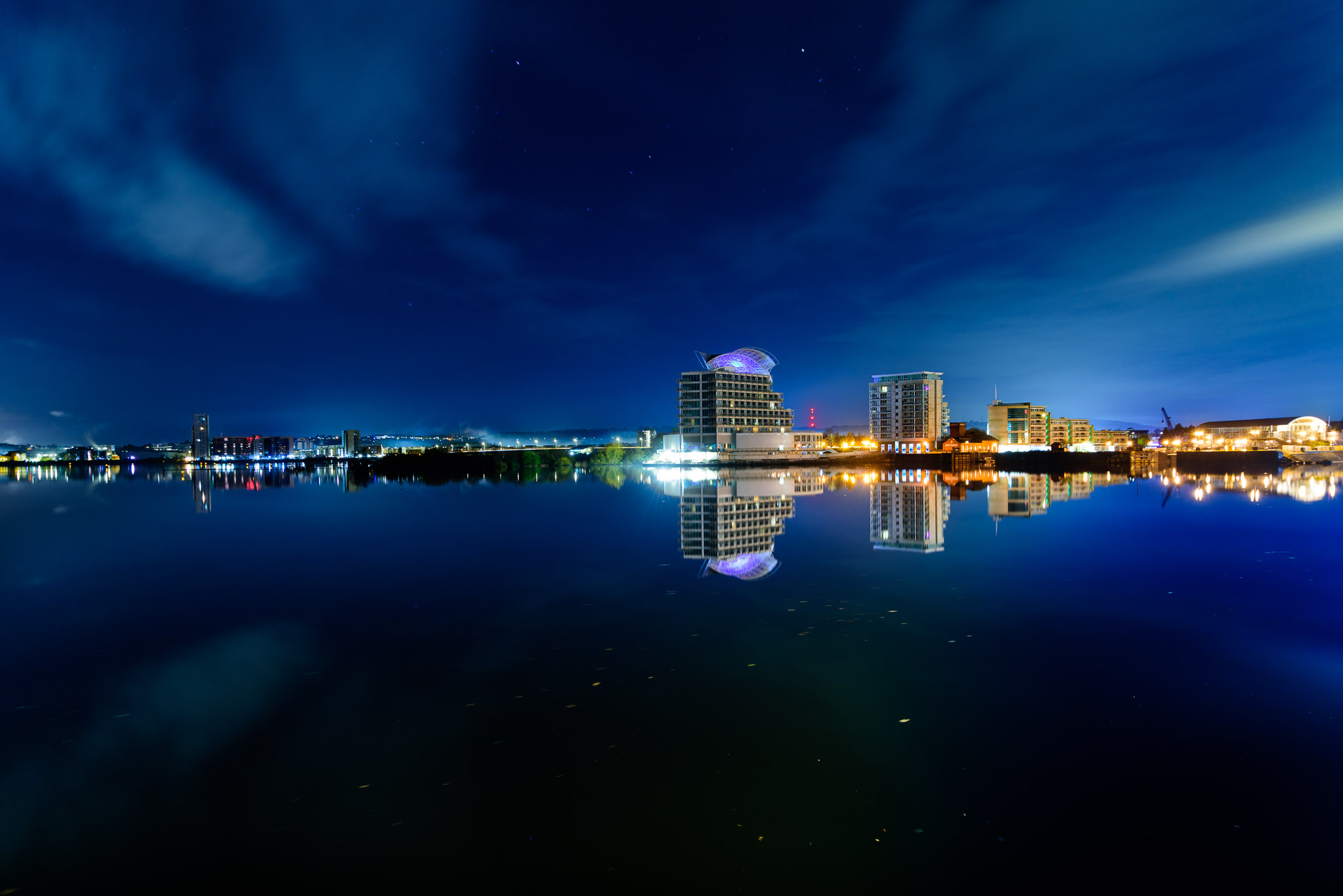 A night view of St David's hotel and surrounding buildings reflected in the still water of Cardiff Bay
