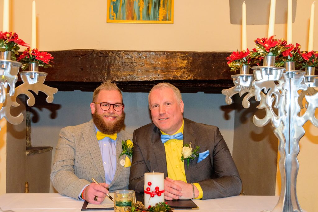 christopher & david sign the register after their wedding ceremony